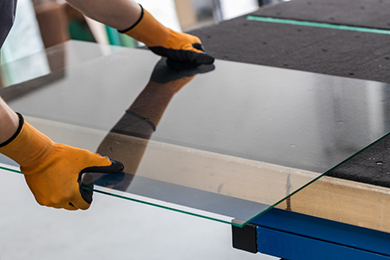 Technician cutting glass sheet for window